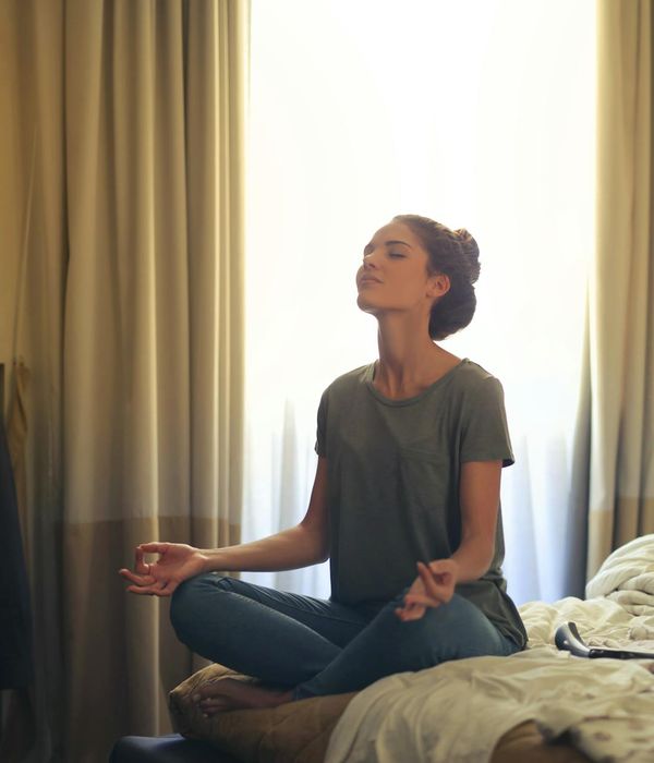 Woman sitting peacefully by a window in a meditative state.